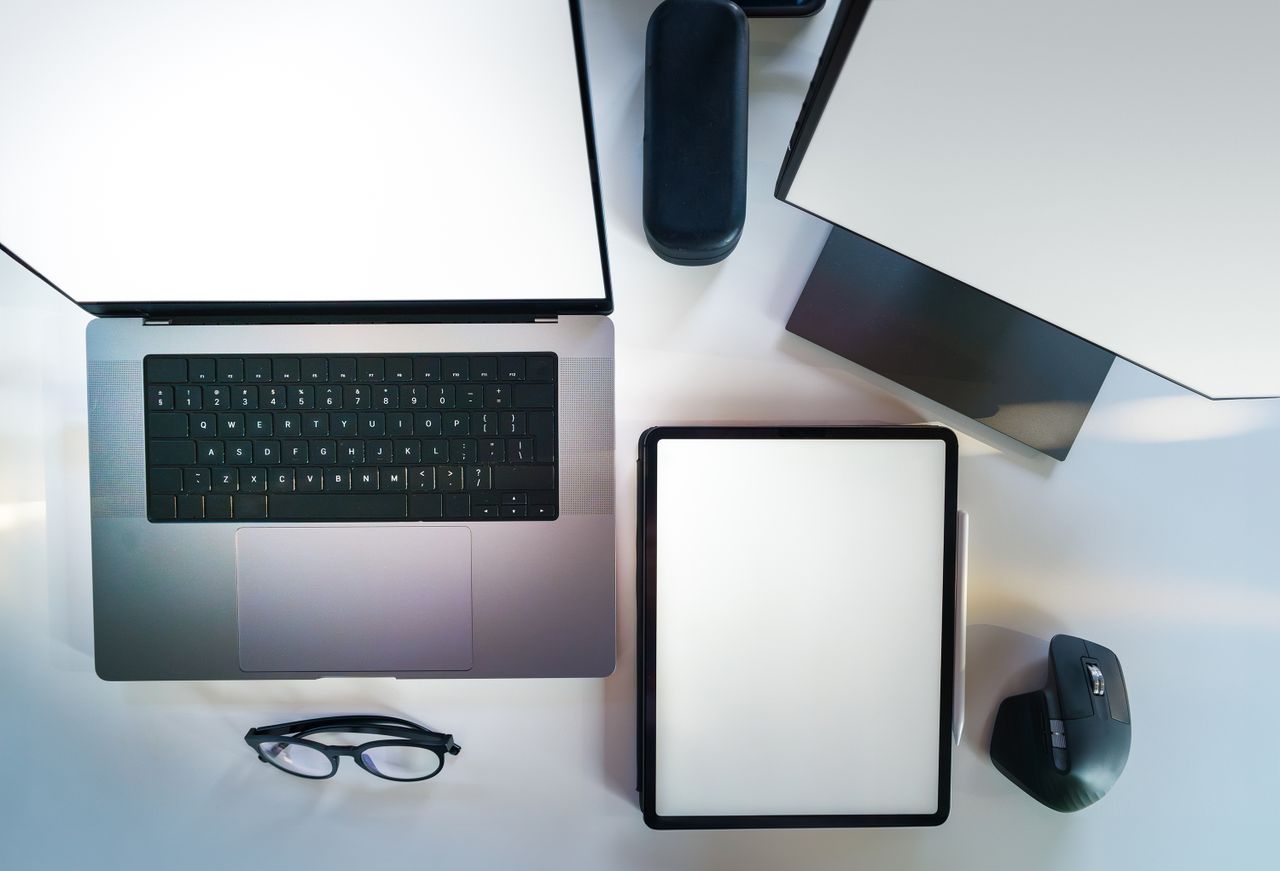 why-choose-us Vue plongeante d’un bureau de travail moderne et élégant, avec un ordinateur portable, une tablette et des accessoires.